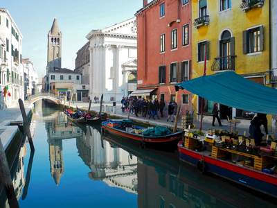 Boats docked on canal edge with street vendors selling merchandise, Venice, Italy