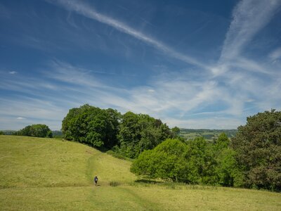 Lone hiker walks on Offa's Dyke Path on a green hill in Wales