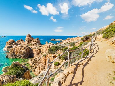 Coastal pathway in Costa Paradiso with view of blue sea and large rocks jutting out close to trail, Sardinia, Italy