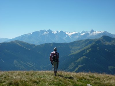 Lone hiker standing near grassy mountain edge admiring mountain landscape in Hochkoenig, Austria